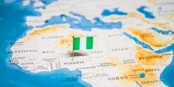 Part of world map with African continent shown prominently. Nigerian flag sticks out of the map to mark where the country is.